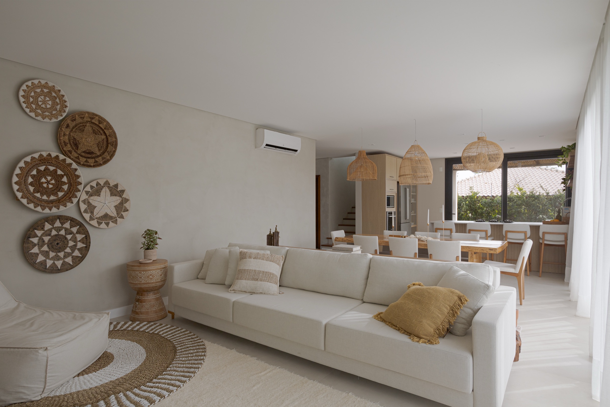 Sala de estar com sofá branco e pratos de fibra trançada na parede